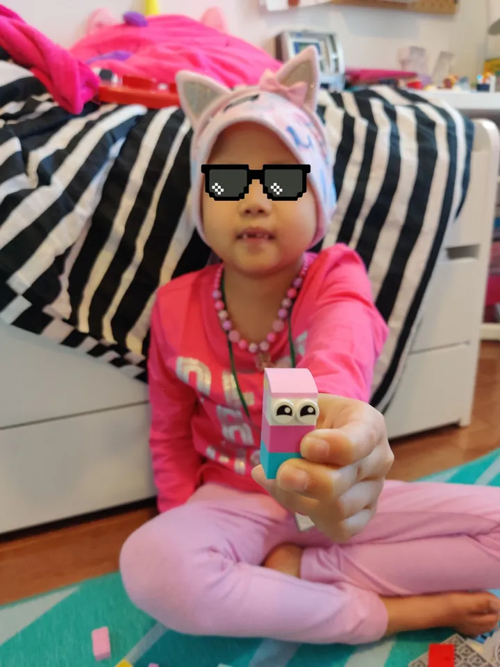 My daughter holds a pink and teal LEGO Ninja-Blok out toward the camera.